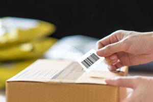hand holding barcode label on shipping box box with barcode
